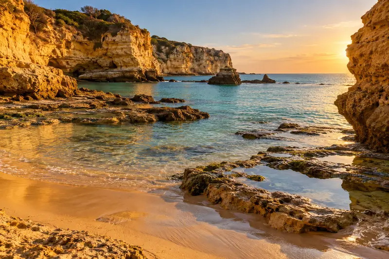 Cala de arena con marea baja entre acantilados de roca ocre al norte de Conil